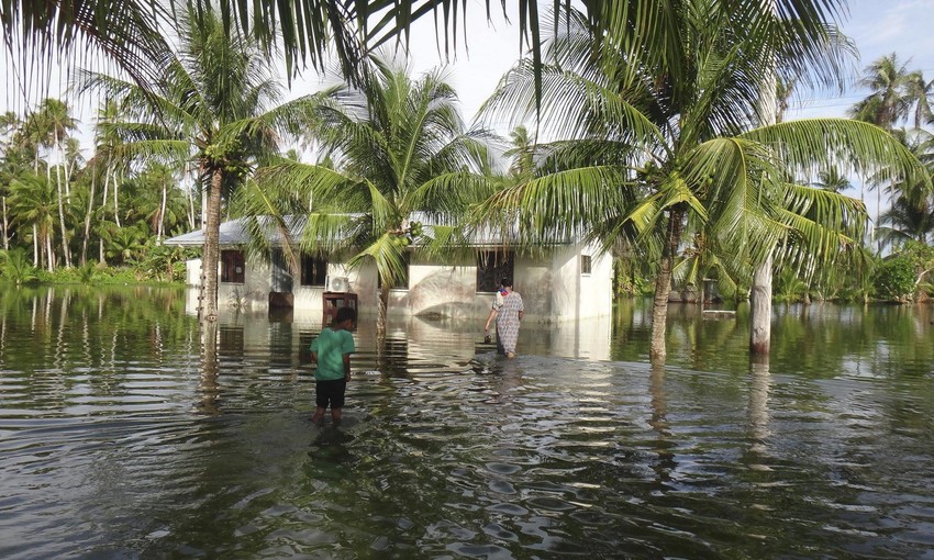 A woman and a child walk through knee-deep water to reach their home during a king tide event on Kili Island in the Marshall Islands. Two king tide events hit the island in 2015, causing massive flooding which left thousands of dead fish to rot after