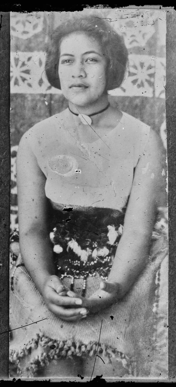 hree-quarter length portrait of Her Royal Highness Princess 'Elisiva Fusipala Tauki'onetuku, daughter of His Majesty King Tupou II and Queen 'Anasēini Takipō, photographed against a tapa cloth backdrop.