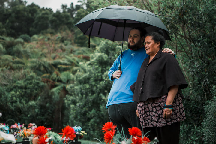 Albert and Lina Fairbrother stand under an umbrella at Taita Cemetery Photo: Saraid de Silva and Julie Zhu