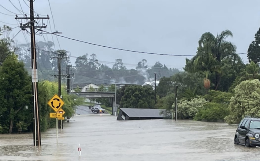 A building on Candia Road in Henderson Valley is swept away in floodwaters. Photo: RNZ / Felicity Reid