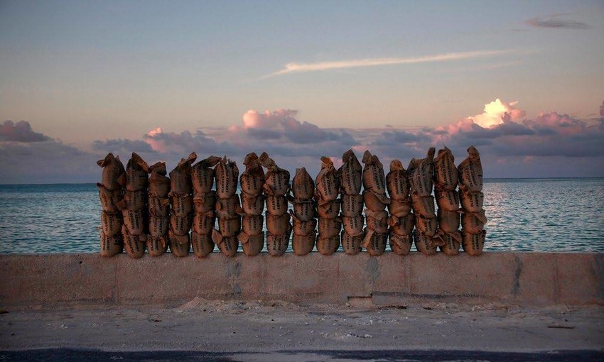 Family members gather rocks and corals from the seabed to build a stone wall as protection against rising sea levels.