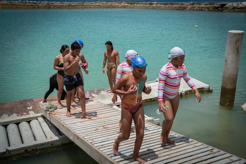Children in Tonga jump out of the water after finishing a swimming session