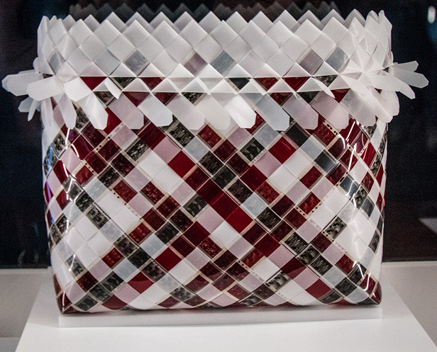 The bag uses Polynesian weaving style but if you look closely it's made out of camera film. The film is of pictures taken of a Polynesian dance group in the Cook Islands